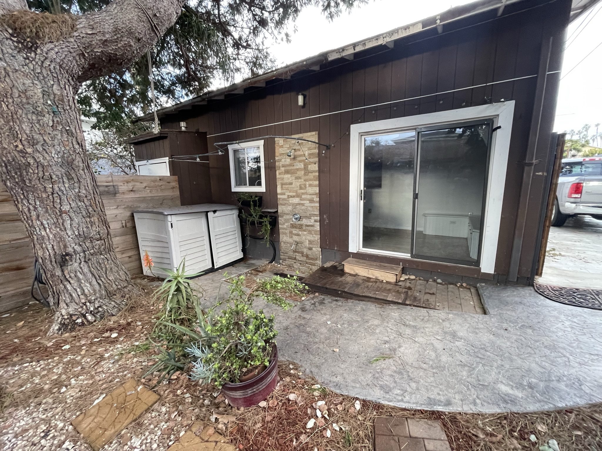 Completed garage conversion ADU courtyard entry with sliding glass door and patio