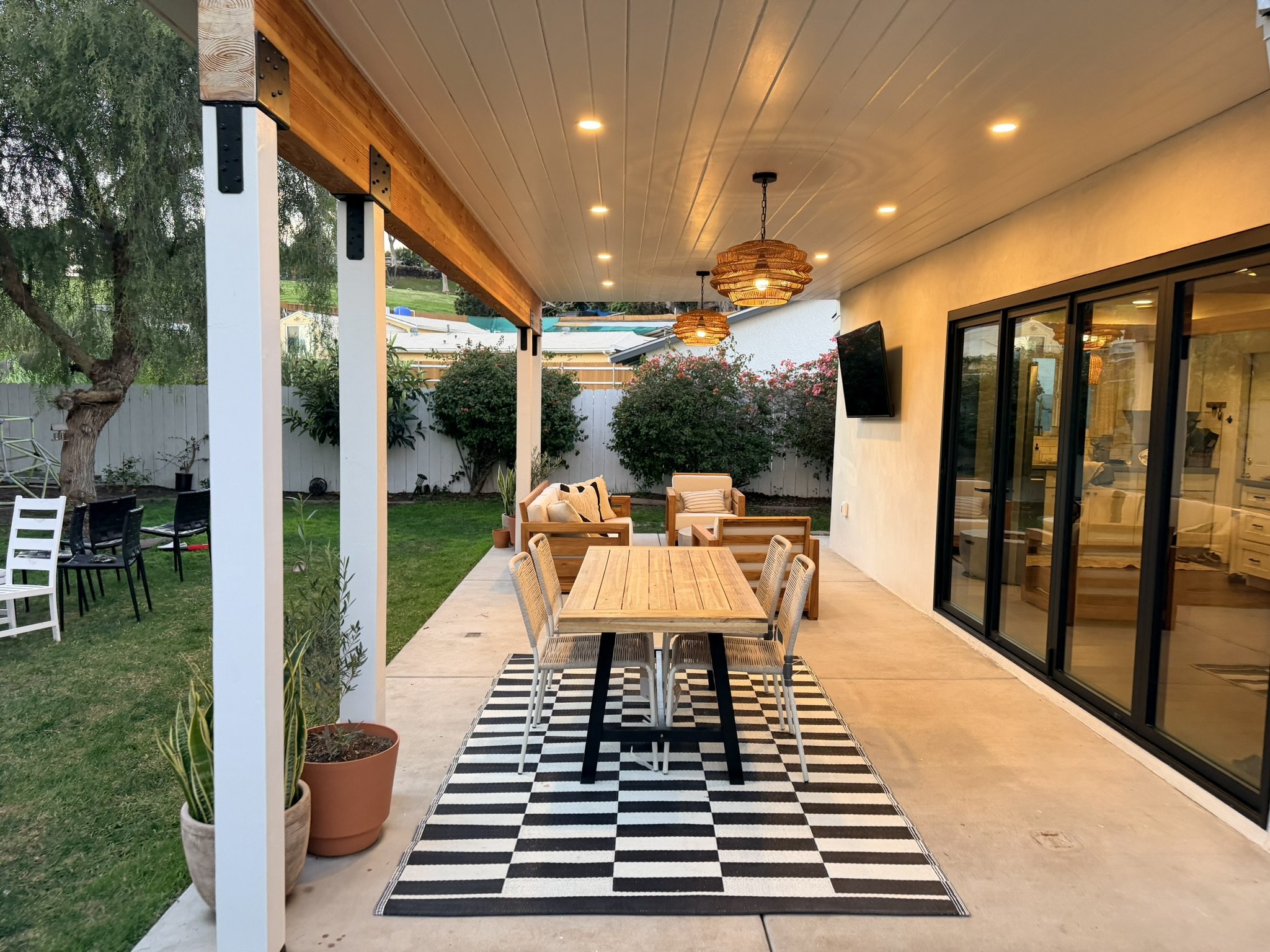 Finished outdoor dining and living area beneath a custom covered patio addition