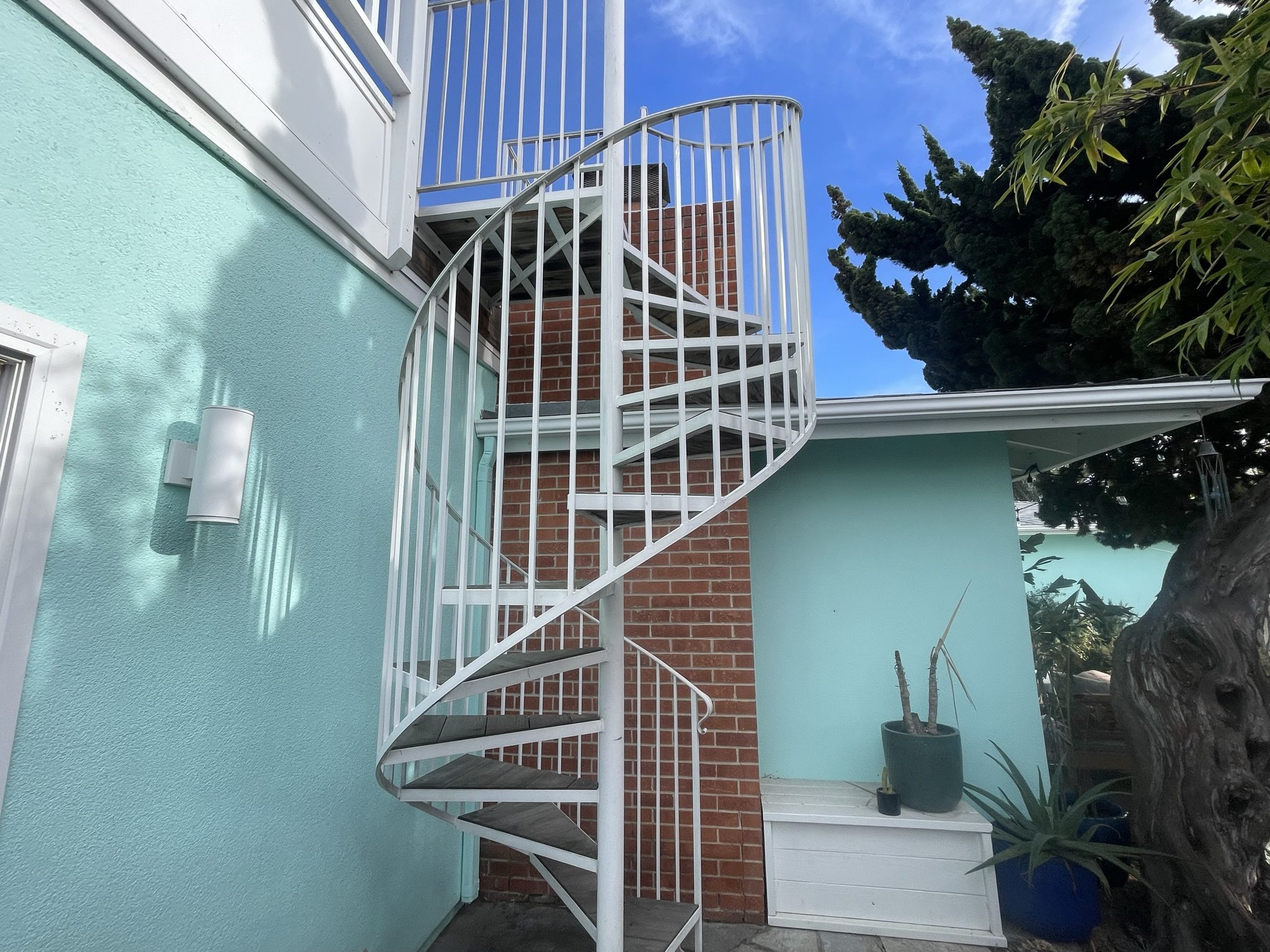 Completed white spiral stair connecting the patio to the upper deck