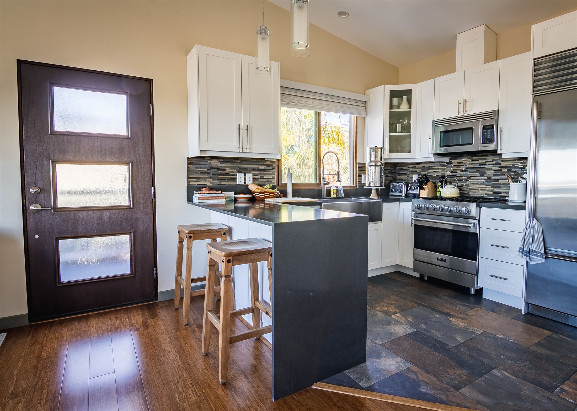 Finished kitchen remodel with white cabinetry, dark counters, and hardwood flooring