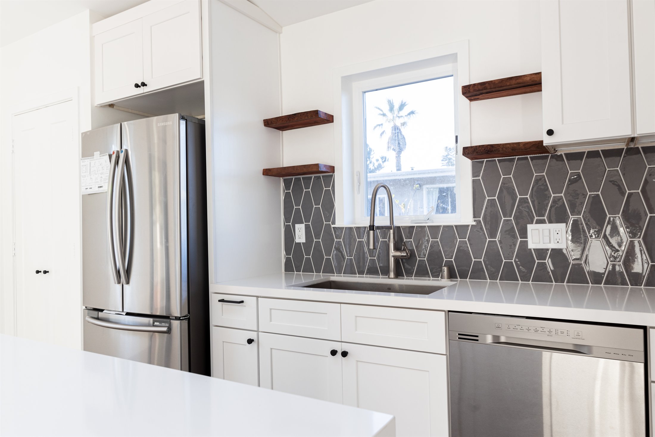 Finished ADU kitchen and dining area beneath a vaulted ceiling with skylights