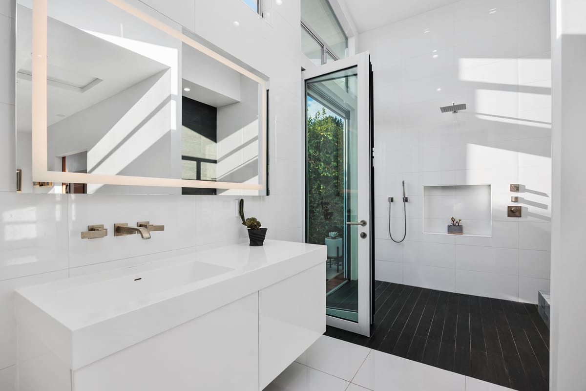 Modern white bathroom with custom vanity and door to an outdoor shower courtyard