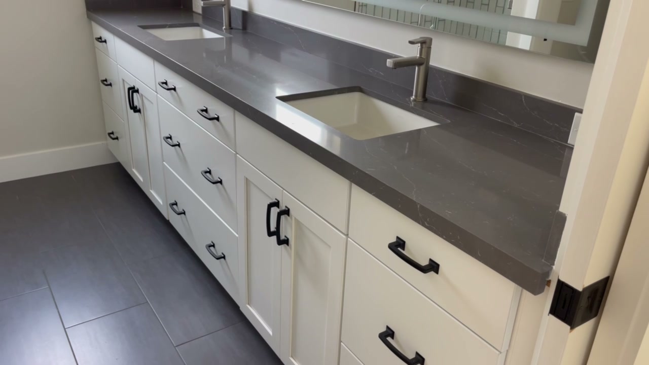 Double vanity with modern cabinetry and dark tile floor in the Encinitas ADU bathroom