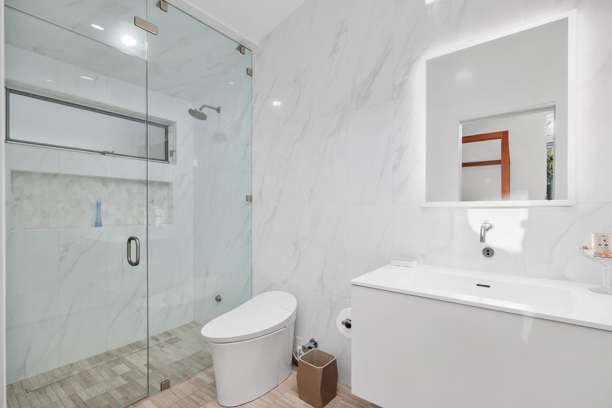 Estrella del Mar remodel: Bright bathroom with a glass shower and clean white finishes.